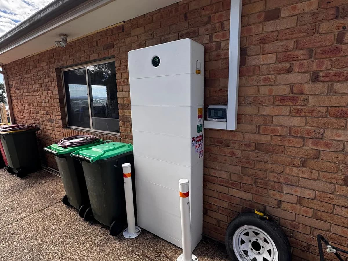 A home battery installed by EFS Solar against a brick wall in Gillieston Heights, protected by bollards