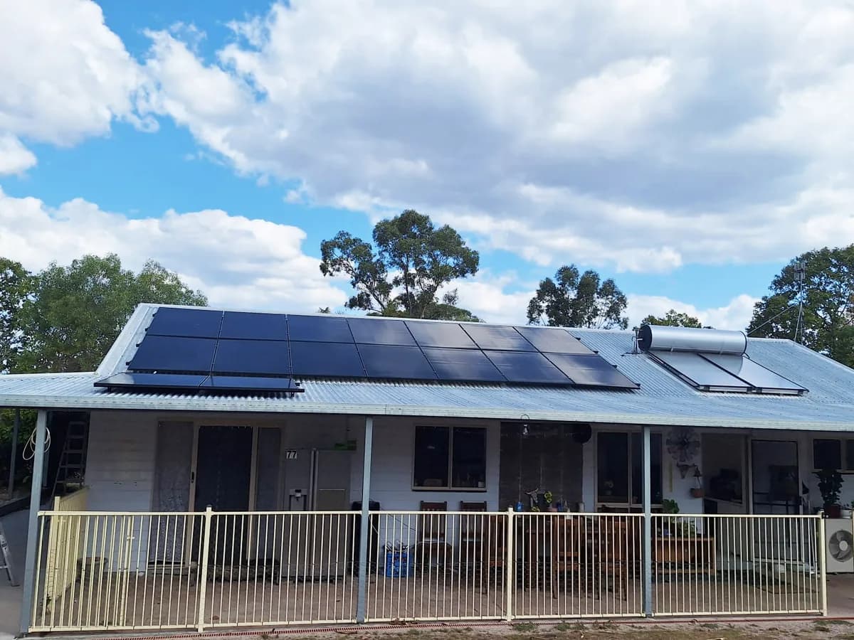 Solar panels and a solar hot water tank across the roof of a rural Miriam Vale home under a blue sky