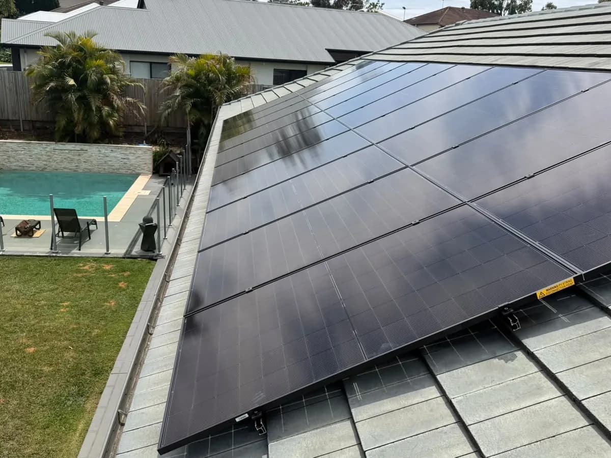 Aerial view of all-black solar panels on a charcoal tiled roof at a North Lakes home, overlooking the pool and backyard