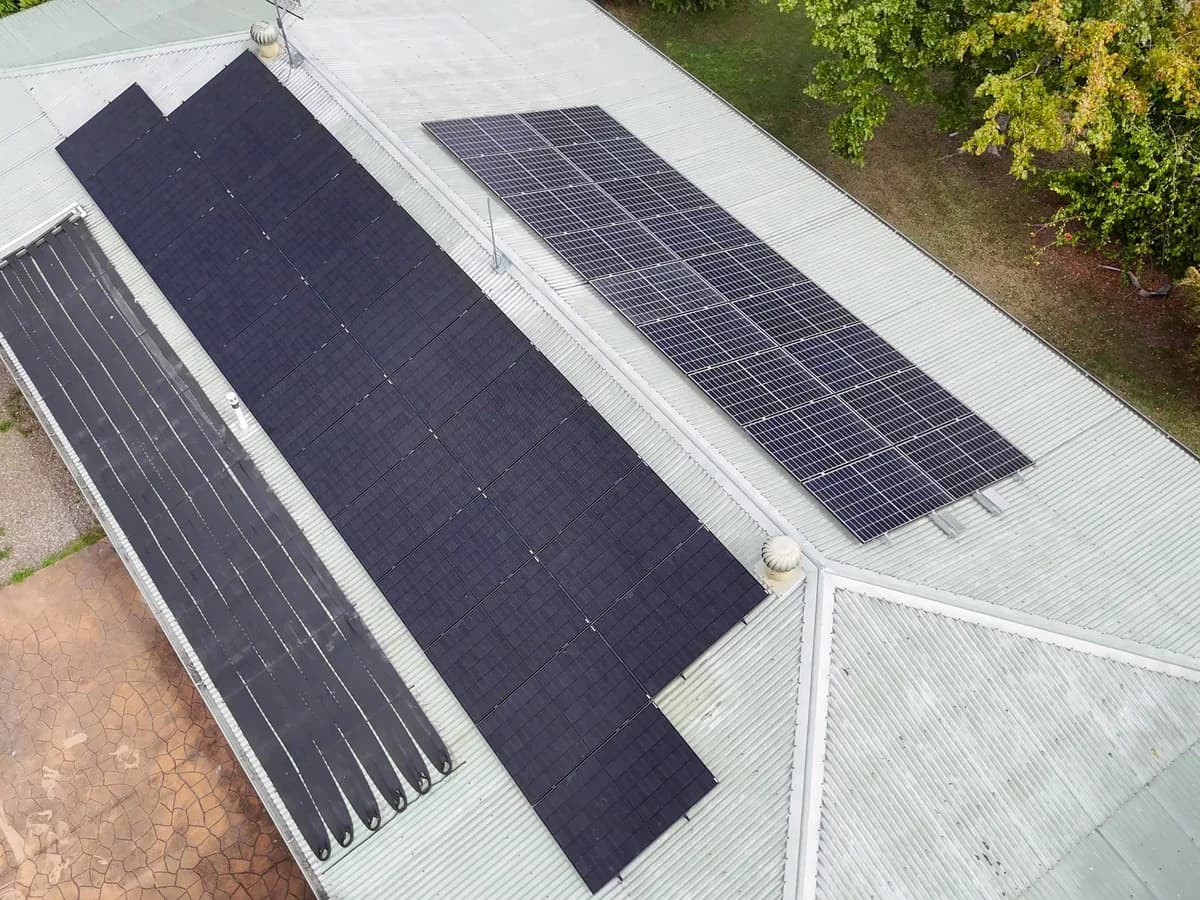 Aerial view of two black solar arrays across a metal roof in Ormeau, at the northern end of the Gold Coast