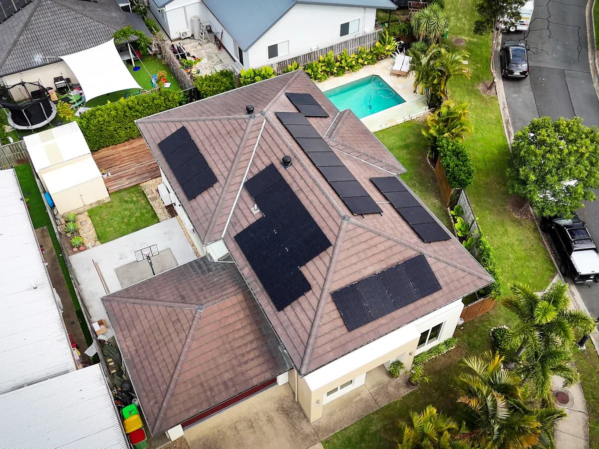 Aerial view of solar panels spread across a tiled roof in a Pimpama estate, with the backyard pool alongside