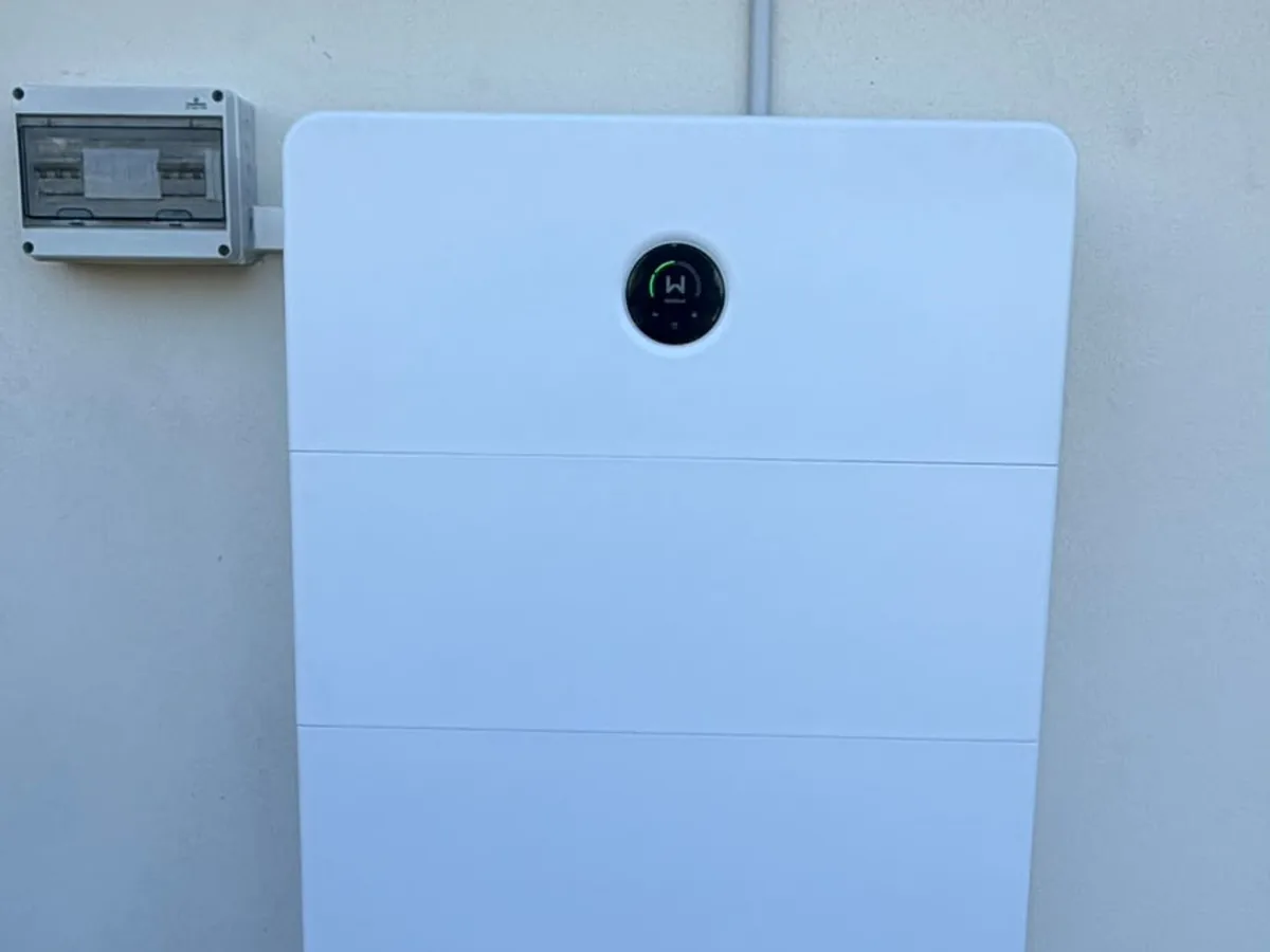 The top of a home battery installed by EFS Solar against a cream wall in Stretton, beside the switchboard