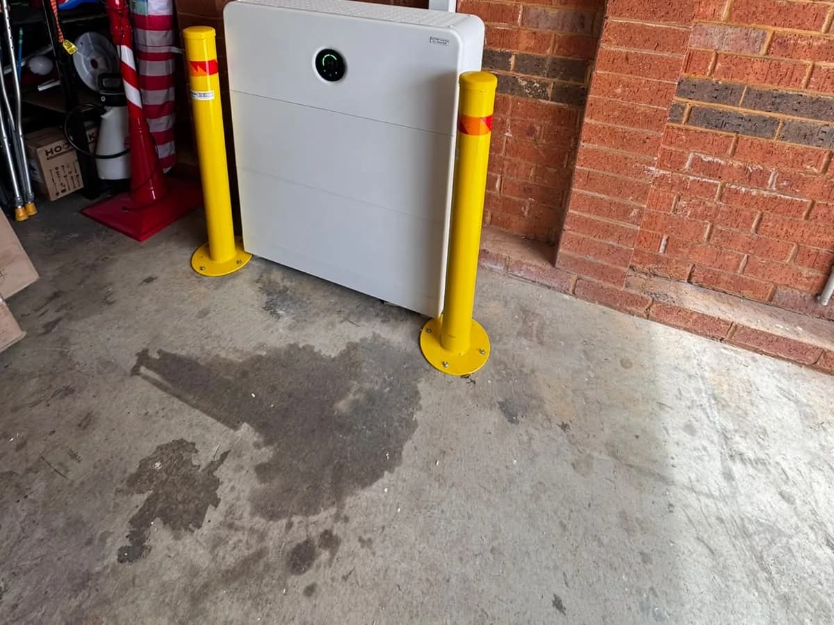 A home battery installed by EFS Solar in a Tahmoor garage, flanked by safety bollards