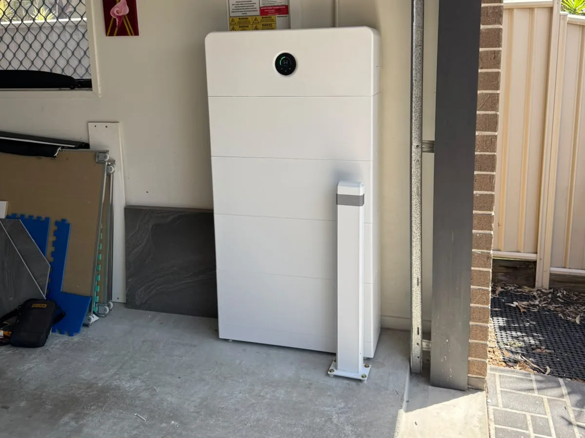 A home battery installed by EFS Solar in a Thornlands garage, with a protective bollard and the shutdown signage above