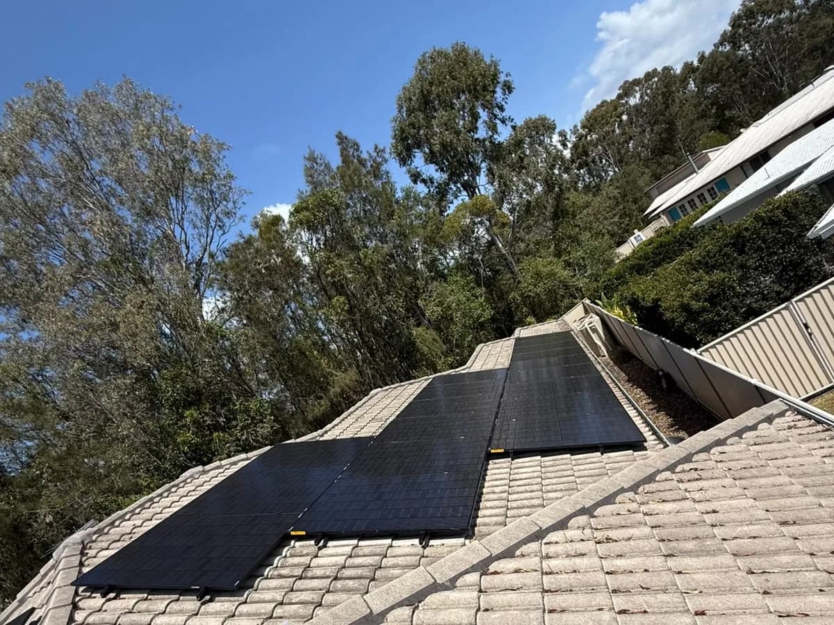 Black solar panels on a concrete-tiled roof in Thornlands, on a bush-backed block with a neighbouring home behind