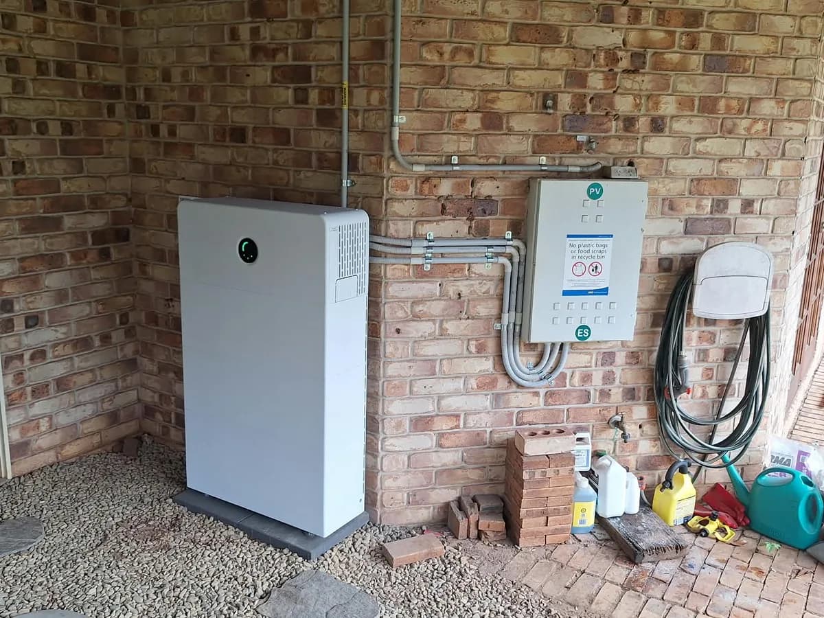 A home battery installed by EFS Solar against a brick wall under a Willow Vale carport, beside the PV and battery isolators